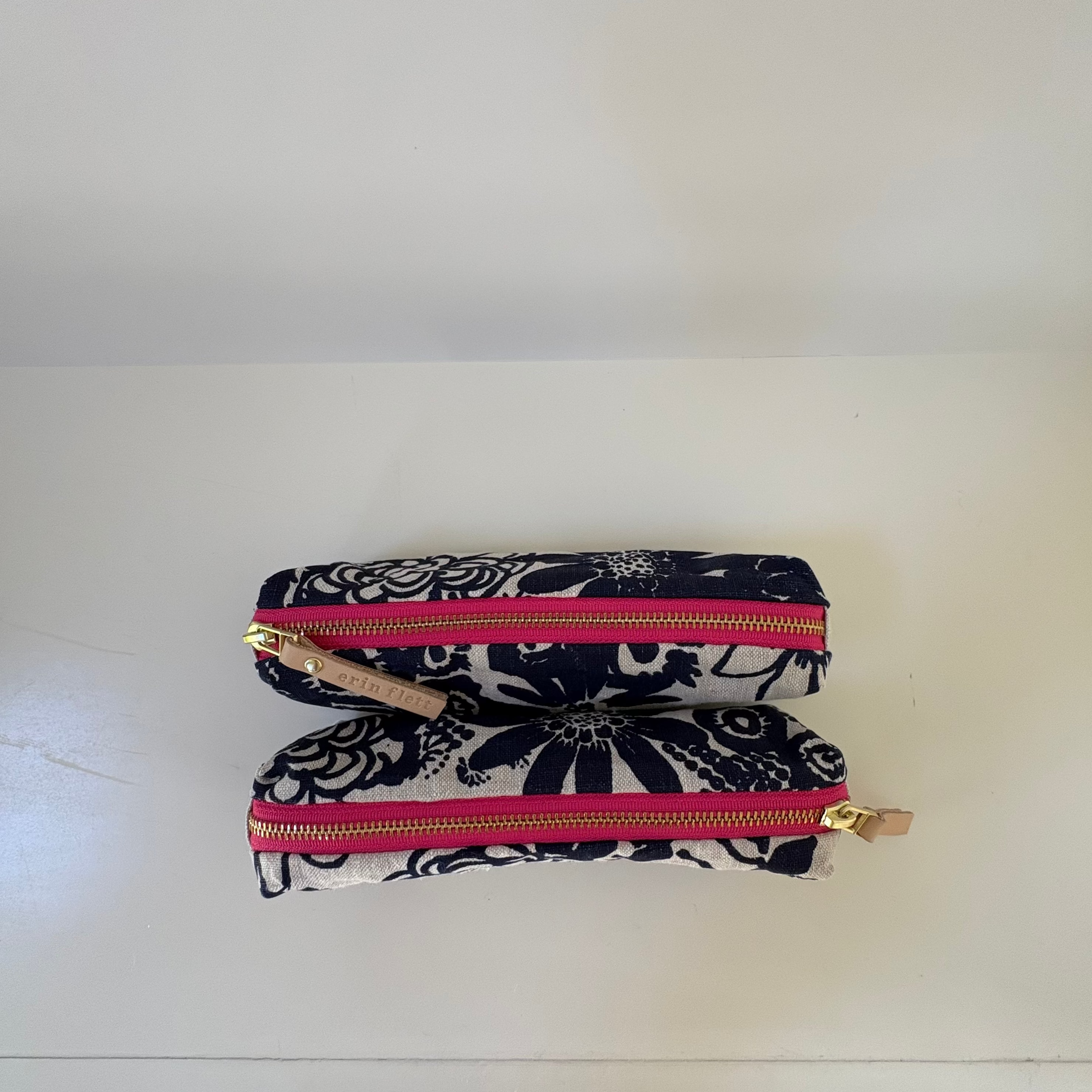 Two floral-patterned pouches with pink zippers on a white surface